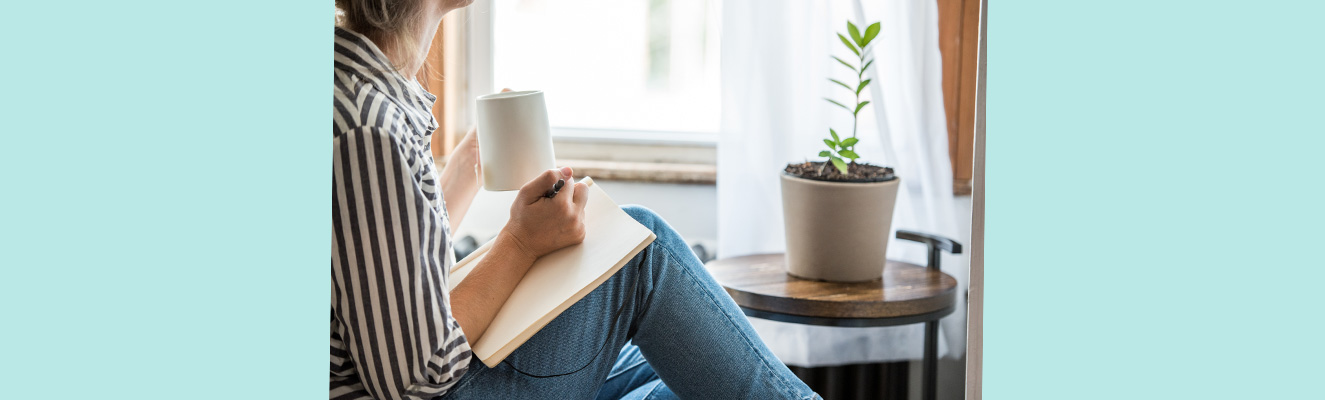 woman sitting down writing on a book