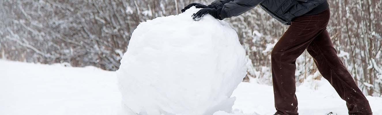 Man pushing snowball up a hill