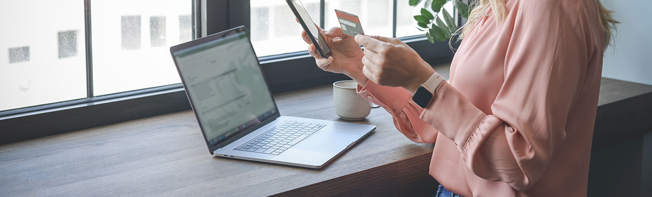 Women standing in front of a computer with a credit card in her hand